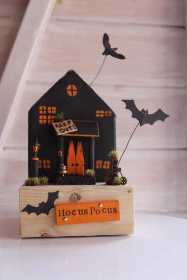 Haunting Halloween decoration featuring a haunted house, bats, and spooky trees.